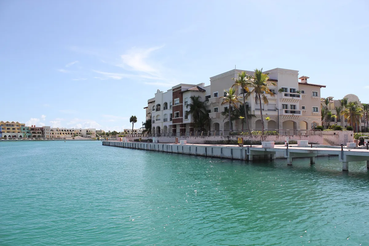 Edificios frente al agua con palmeras junto al agua turquesa de la marina de Cap Cana en República Dominicana